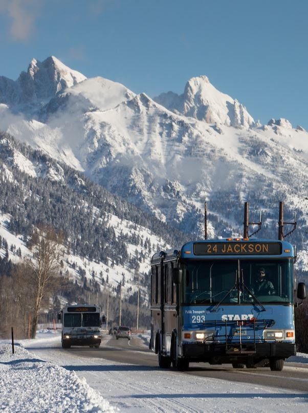 START buses driving on 22 in Winter with Tetons in background